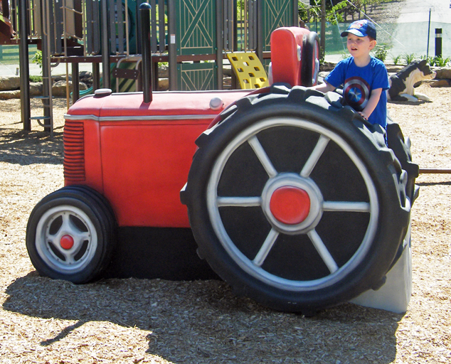 Kid sitting on tractor in Showman's Circle Farm-themed play area at Lake Metroparks Farmpark